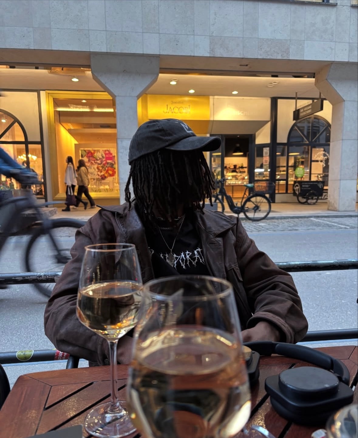 Künstler Dews Pegahorn im Look der King Corporation Streetwear-Kollektion mit Wein im Restaurant
